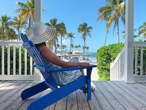 Woman sitting in a blue Adirondack chair overlooking the beach