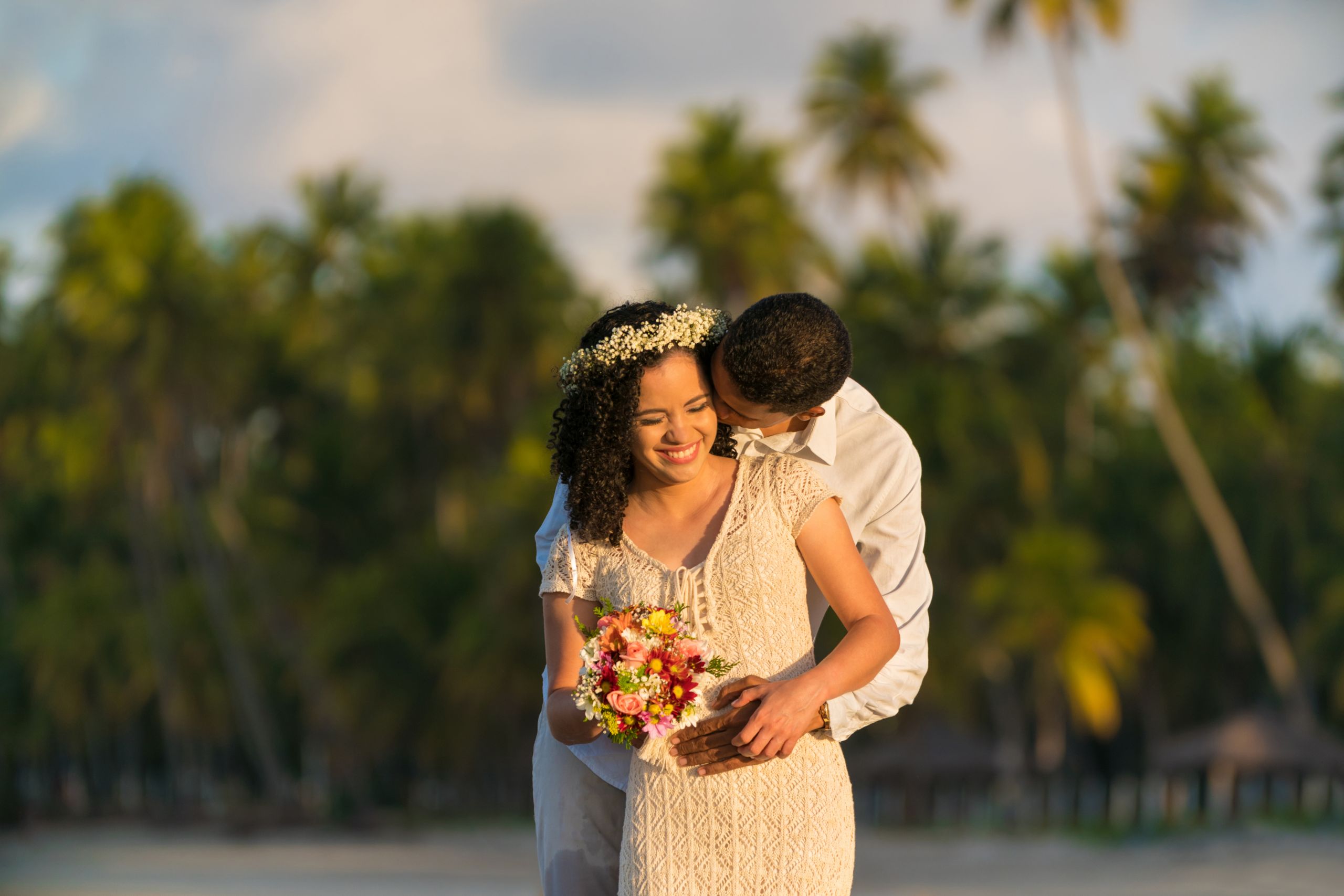 Newlyweds on beach with bouquet and flower crown