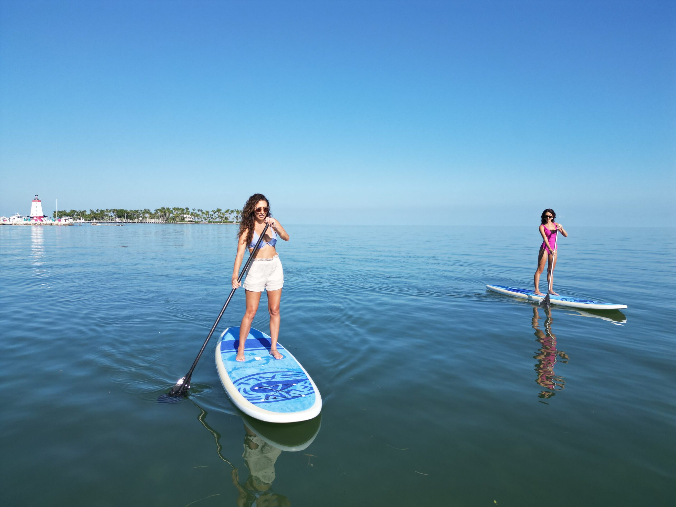 guests enjoying paddle boarding on blue, calm water at Tranquility Bay Beachfront Resort
