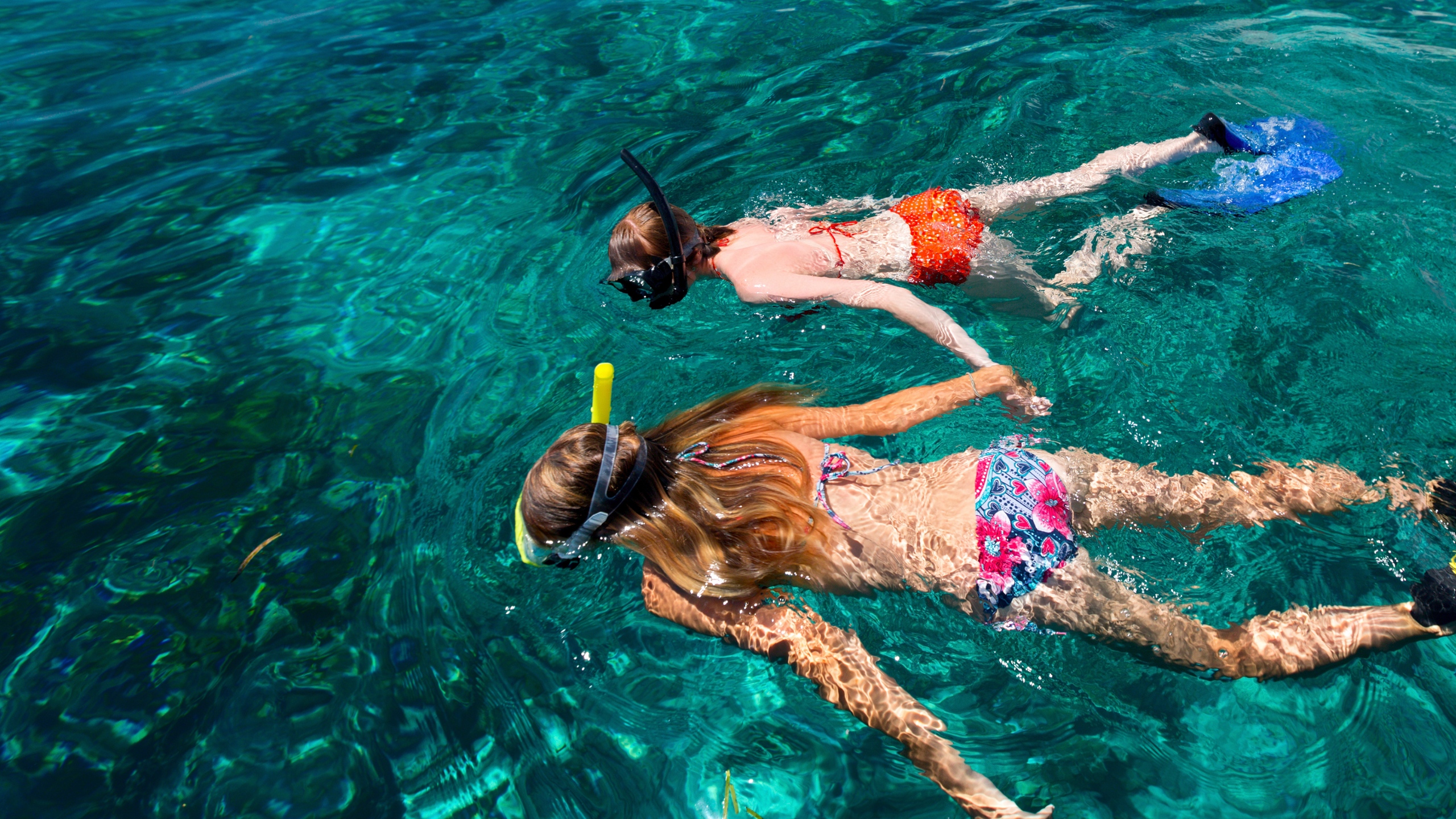 Two girls snorkeling in turquoise water.