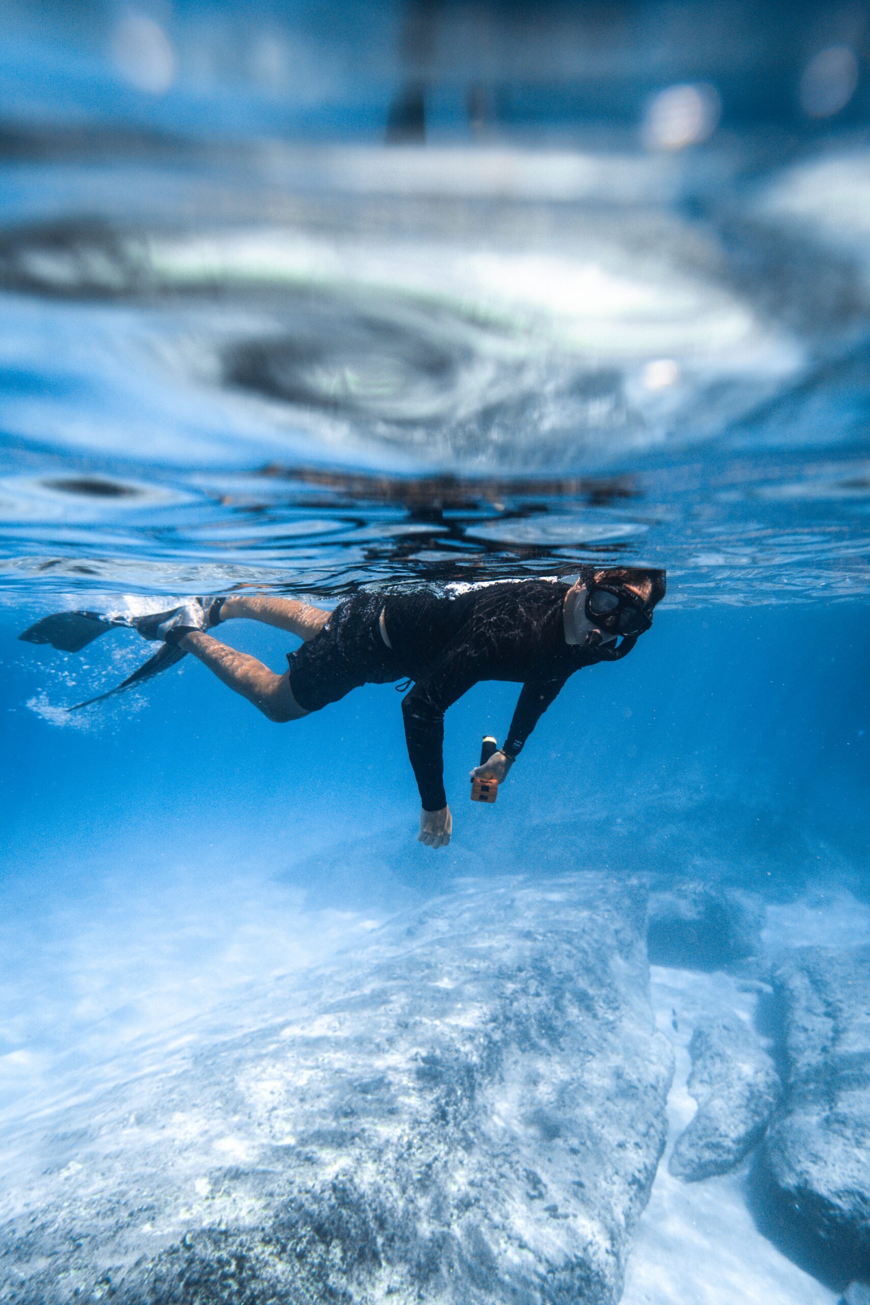Snorkeler in mask and fins swimming over rocks in clear blue Florida Keys water