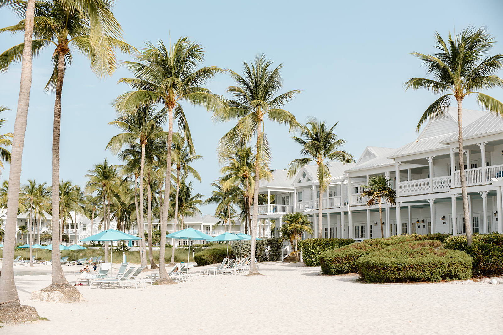 wide shot of tranquil beachfront with villas and beach umbrellas on white sand