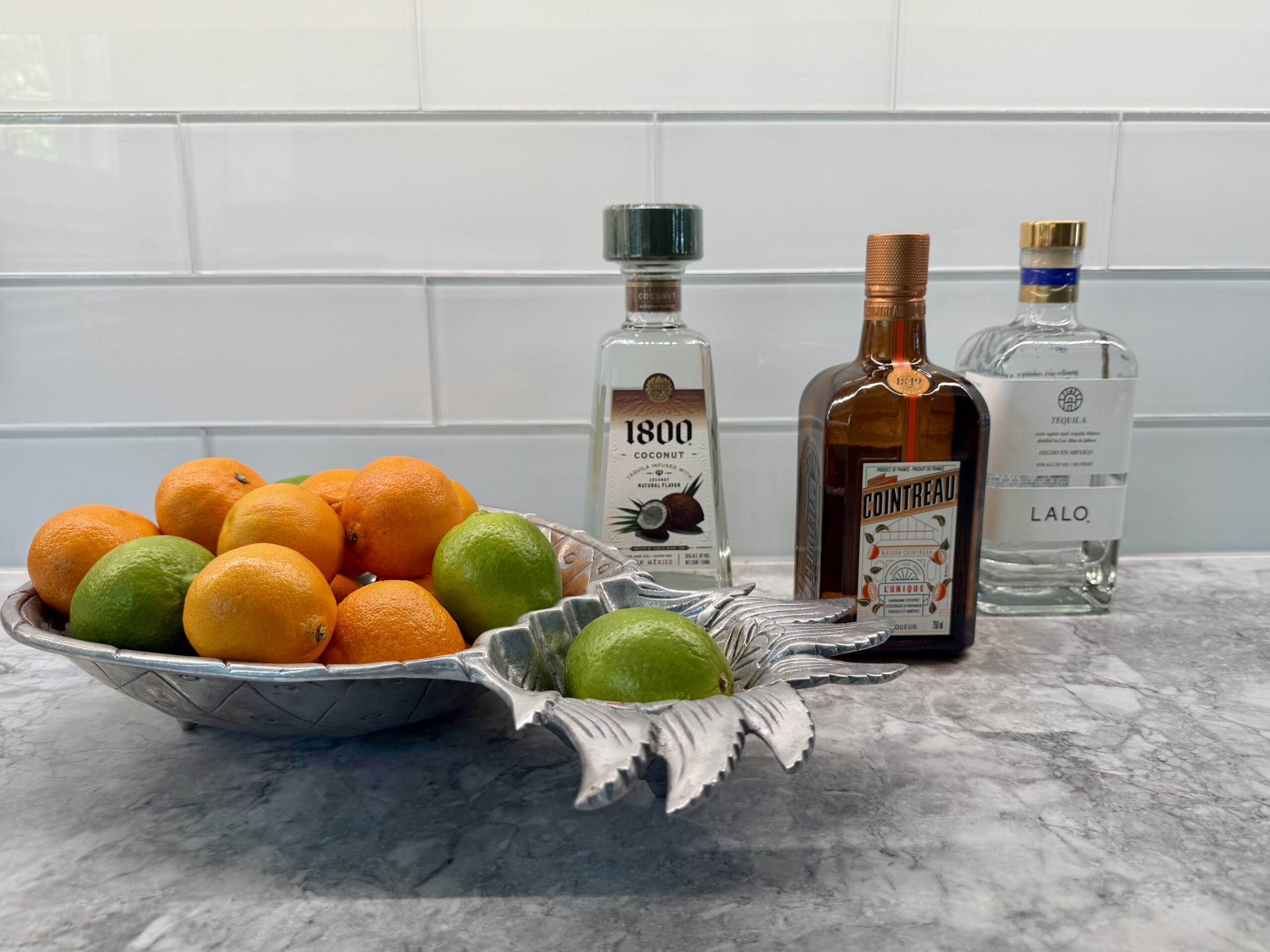 Limes, oranges and tequila on a kitchen counter